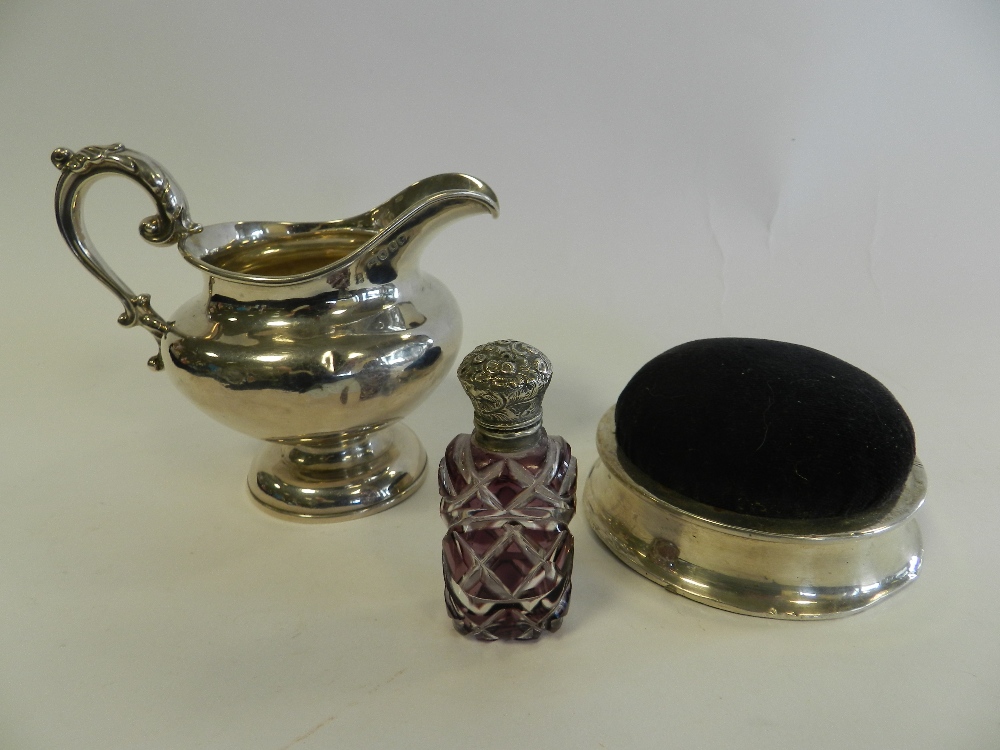 A silver mounted pin cushion together with a silver cream jug and a purple glass silver topped