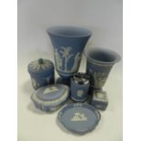 Five trays of blue Wedgwood Jasper ware including vases, table lighters, boxes and covers,