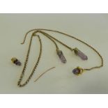 A rough amethyst crystal pendant with yellow metal chain together with further mounted rough