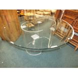 A large circular glass table top with bevelled edge on two Perspex crescent supports