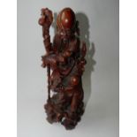 A Chinese carved hardwood figural group of an immortal