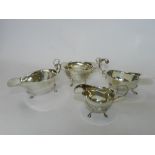 Two silver sauce boats together with a silver cream jug and sugar bowl