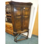 A Carolean style oak double door corner cabinet on stand with barley twist legs 75cm wide,