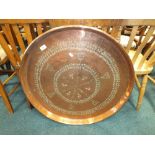 A Middle Eastern copper tray with foliate design and up-turned rim,