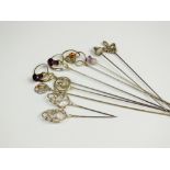 A collection of silver, white metal and brass hat pins,