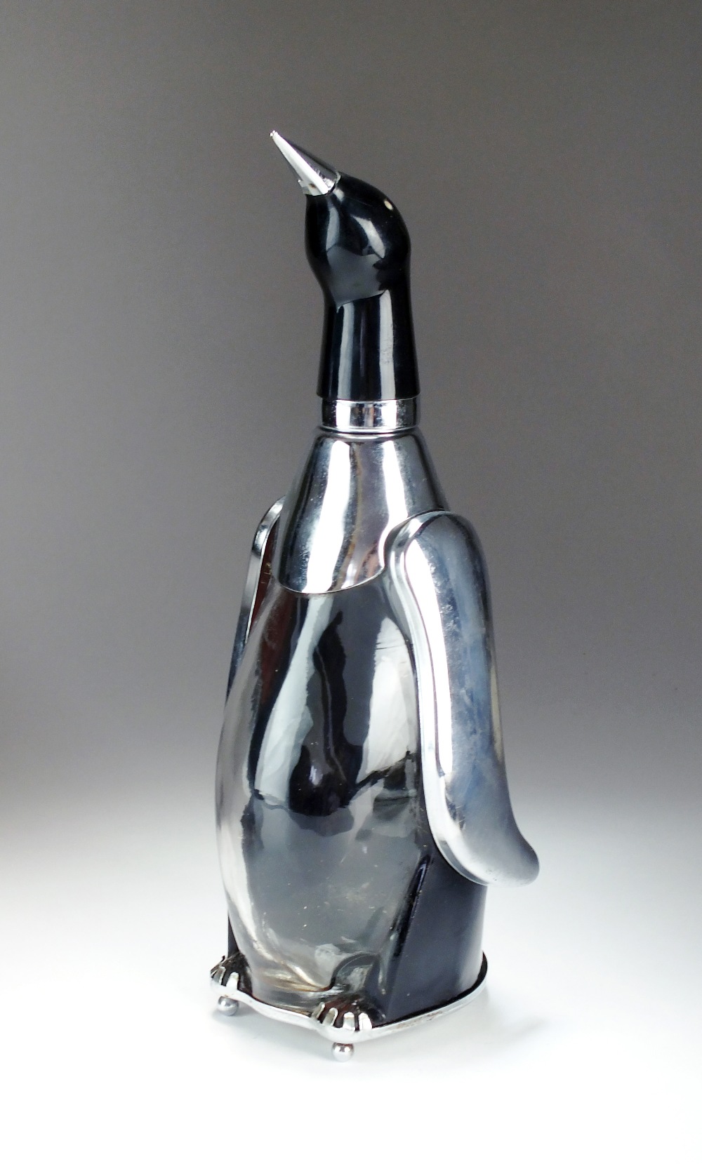 A novelty glass and chromium plated musical spirit decanter in the form of a penguin,