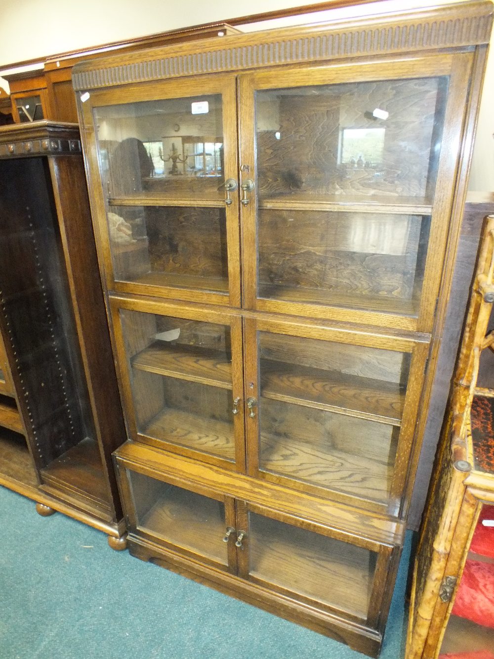 An oak tiered freestanding bookcase with two glazed cabinet doors enclosing an adjustable shelf