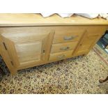 A modern light oak sideboard with three central drawers flanked by fielded cupboard doors,