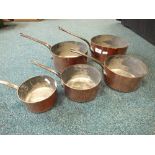 A graduated set of five copper and steel sauce pans