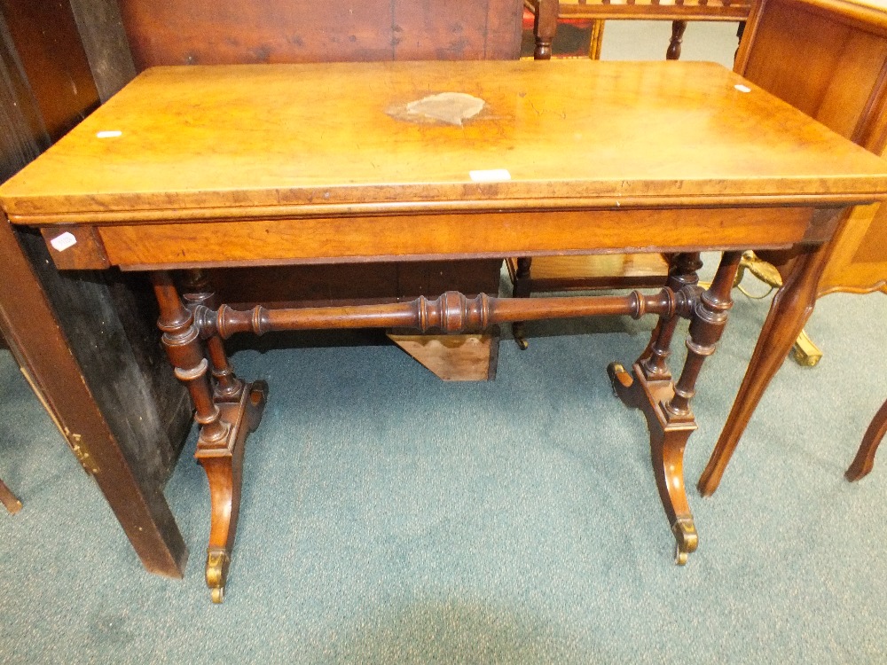 A Victorian figured walnut card table the rectangular fold over swivel top with a baize lined