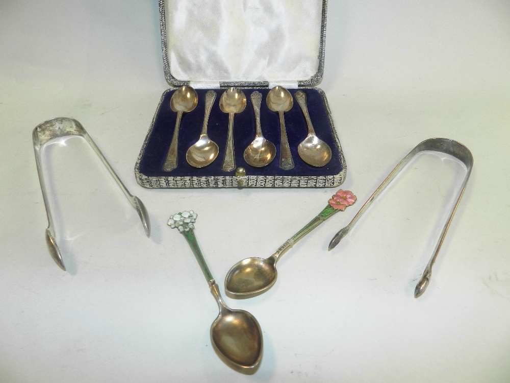 Two silver gilt and enamelled spoons with floral terminals together with two pairs of silver sugar