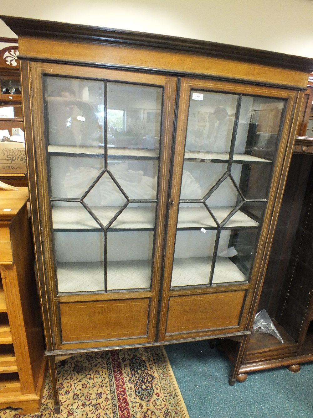 An Edwardian mahogany display cabinet with two ribbed glazed doors enclosing lined shelves between