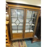 An Edwardian mahogany display cabinet with two ribbed glazed doors enclosing lined shelves between