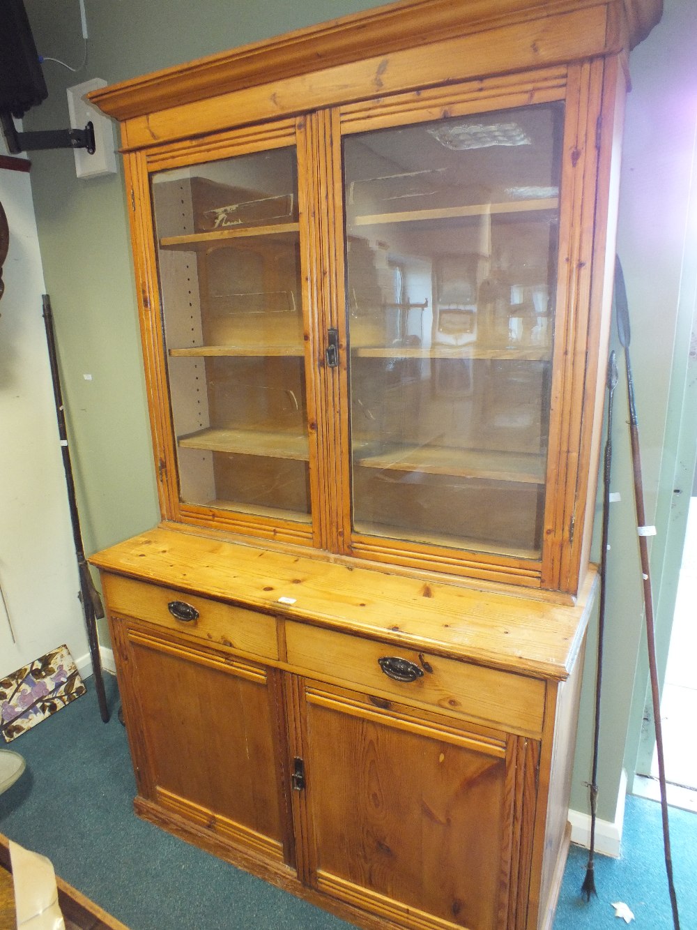 A stripped pine kitchen cabinet, early 20th century with moulded cornice above two glazed doors,