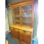 A stripped pine kitchen cabinet, early 20th century with moulded cornice above two glazed doors,