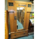 An Arts and Crafts oak wardrobe in Liberty's style with single mirror door and strap hinges between