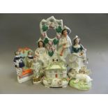 A collection of Staffordshire figures including bower groups, a clock group, a pair of bocage deer,