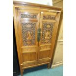 A Japanese elm two door cabinet the pierced doors detailed with a Bijin and fan panels enclosing