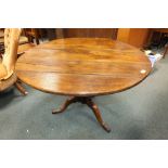 An oak tilt top tripod table on gun barrel column and three down curved legs,