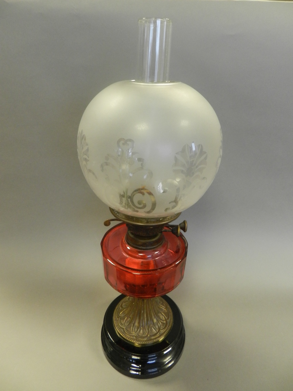 A brass and glass oil lamp, circa 1900, with cranberry reservoir,