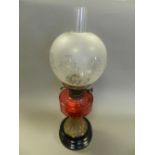 A brass and glass oil lamp, circa 1900, with cranberry reservoir,