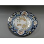 A Japanese Imari oval dish, Meiji period, decorated with lion dogs cavorting amid flowering plants,