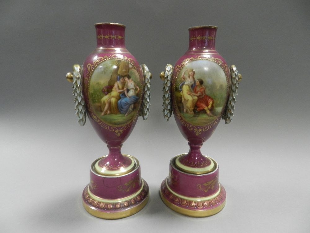 A pair of Vienna porcelain vases of amphora shape on pedestal bases and painted in colours with