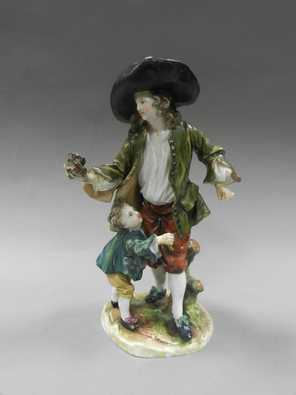 A Continental porcelain figure group of a rustic man with young boy holding flowers