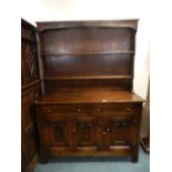 An oak Priory style dresser with two height rack above two notched drawers and three arcaded panel