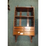 A n Edwardian mahogany wall shelf with open fretwork sides and three graduated narrow drawers,