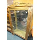 A Louis XV style gilded display cabinet with three internal glass shelves on squat shaped feet,