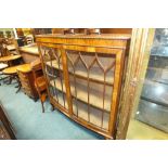 A figured walnut bow front two door display cabinet with lined shelves on cabriole legs and claw