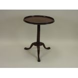 A George III and later mahogany tilt top tripod table with turned raised rim on a slender pilaster