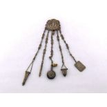 A white metal Victorian chatelaine with five chains carrying a scissors case, a propelling pencil, a