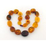 An amber necklace, composed of large polished flattened off round transparent and opaque beads, to a
