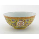 A Chinese ceramic famille rose yellow ground deep bowl on a circular foot rim, decorated with four