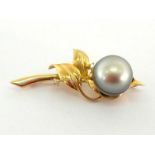 A Tahitian cultured black pearl and diamond brooch, the large circled pearl 13.6mm, off set in a