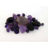 A group of cut and rough amethysts, including cabochon cut stones, tumble polished stones, drilled