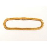 A yellow metal (tests 18 carat gold) fringe necklace, composed of obliquely set textured rectangular