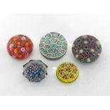 A group of five paperweights comprising four millefiori and one solid cane paperweight, one in