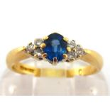 An 18 carat gold, sapphire and diamond ring, the central oval cut sapphire 4.8mm long, to a