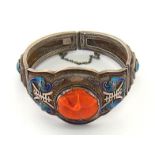 A Chinese enamel and coral bracelet, set to the centre with a carved coral disc modelled as a