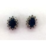 A pair of sapphire and diamond cluster ear studs, the oval cut sapphires 7 x 5mm, in a surround of