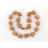 An Italian 18 carat gold and coral necklet, composed of openwork 'petalled' links with a carved