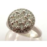 A diamond cluster ring, the circular cluster composed of calibre and brilliant cuts, the cluster