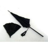 A Victorian black silk parasol, circa 1880 with carved ebonised handle and woven tassels, together