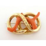 A Victorian gold and coral brooch, composed of a double loop, foliate chased to the centre, a