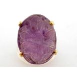 A 9 carat gold and carved amethyst ring, the large oval cabochon 24 x 17mm, carved with a flower,