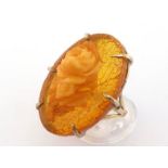A carved amber dress ring, the oval amber with applied carved amber rose, 3.3cm long, the shank