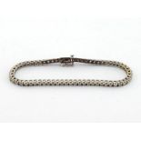 An 18 carat white gold and diamond line bracelet, composed of sixty three uniform brilliants